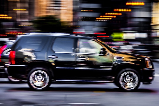 Black SUV speeding down a road in downtown Chicago